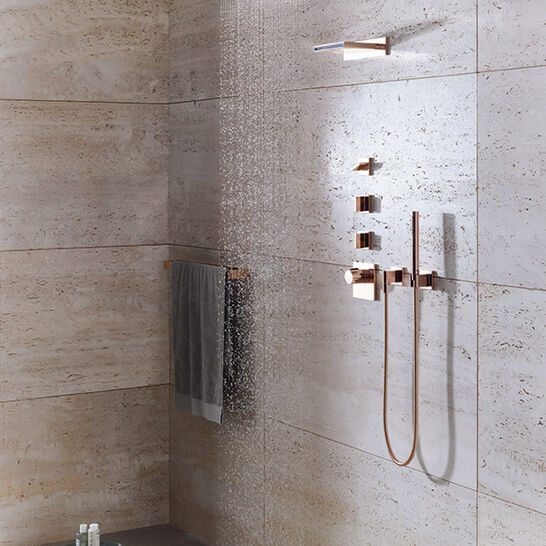 Moderne Dusche mit Regenbrause und roségoldenen Armaturen. Natursteinwände verleihen ein elegantes Ambiente. Handtuchhalter und Ablage für Duschutensilien. Moderne Dusche mit Regenbrause und roségoldenen Armaturen. Natursteinwände verleihen ein elegantes Ambiente. Handtuchhalter und Ablage für Duschutensilien.